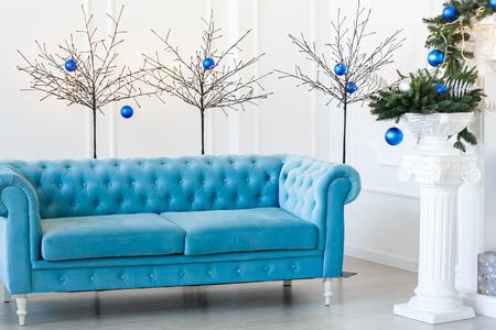 Christmas morning, copy space. Classic apartments with blue buttoned sofa, decorated fir tree. Christmas interiorの写真素材