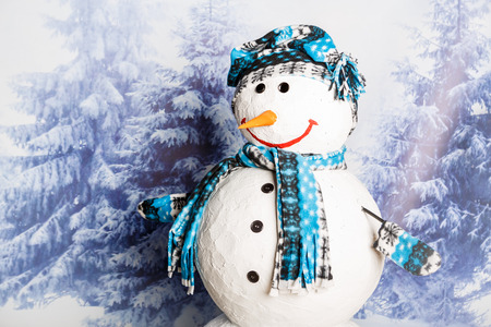 Smiling, happy snowman surrounded by winter landscape with falling snowの写真素材