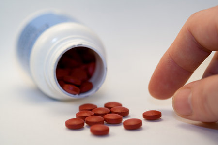 hand taking a red pill from a group of pills