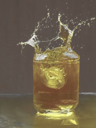 Ice cubes splashing into glass of tea  with Background blurの写真素材