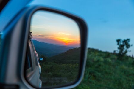 Sunset is reflected in the cars rear-view mirror.の写真素材