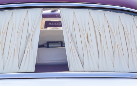 the back window of a historic car with a cream curtain.の写真素材