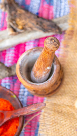 Ethnic wooden mortar with spices inside, standing in a natural rural settingの写真素材