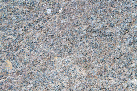 The texture of the granular granite in the photo shows a light stone with a fine granular structure. The stone has a uniform grain distribution, creating a smooth but textured appearance, with shadesの写真素材