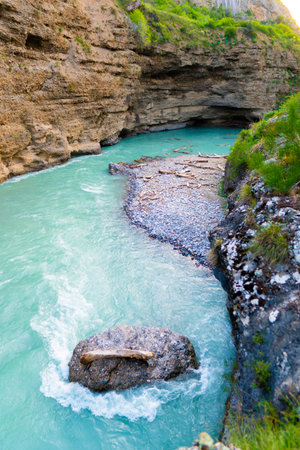 Turquoise mountain river with rapids flowing between cliffs, top view of gorge and rocksの写真素材