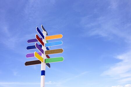 Empty wooden signpost with colorful arrows on blue sky backgroundの写真素材