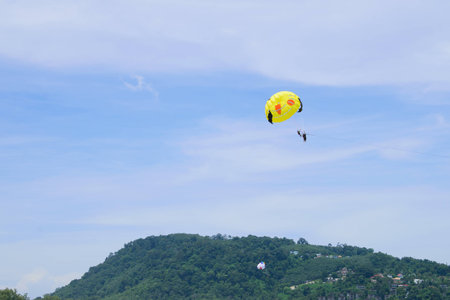 Parachute floats in the sky above the green mountains.の写真素材