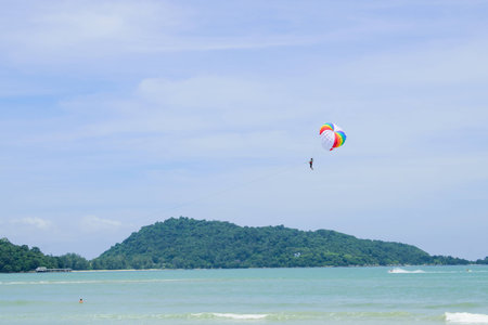 Parachute floats in the sky above the green mountainsの写真素材