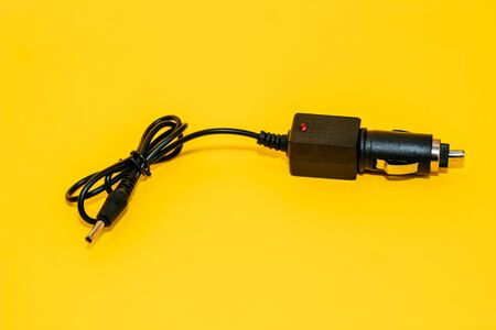 new black cigarette lighter plug on a yellow backgroundの写真素材