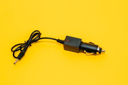 new black cigarette lighter plug on a yellow backgroundの写真素材