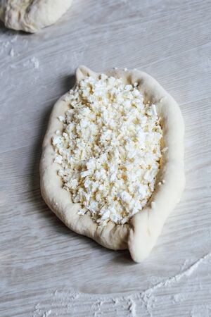 Homemade Ajarian Khachapuri with Suluguni Cheese. Stage of work. Preparation for baking. Raw Suluguni before bakingの写真素材