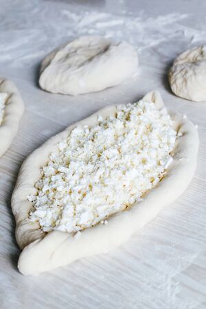 Homemade Ajarian Khachapuri with Suluguni Cheese. Stage of work. Preparation for baking. Raw Suluguni before bakingの写真素材