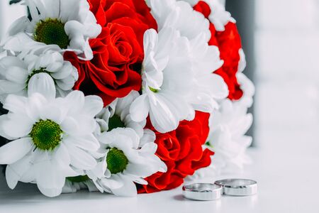 Wedding details bouquet of red and white roses with white gold wedding ringsの写真素材