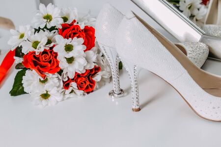 Wedding decor, details of the morning of the bride. White shoes in rhinestones and wedding ringsの写真素材