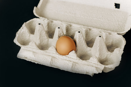 chicken eggs in a paper gray crate on a black backgroundの写真素材