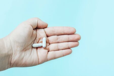 two white tablets on the female palm. Medication space for textの写真素材