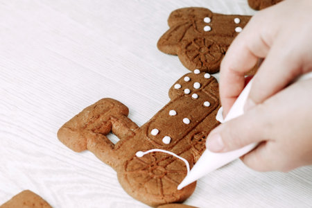 Christmas gingerbread cookies painted with icing sugar. Confectioner girl paints cookies