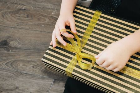 child opens holiday gift in striped gift wrapの写真素材