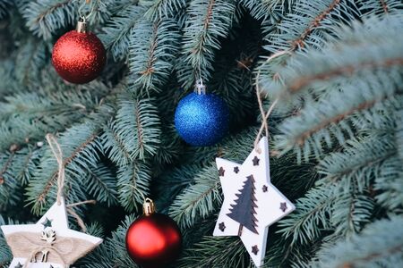 Christmas toy on the branches of a New Year tree. Christmas tree decorated with a festive ball and wooden toysの写真素材