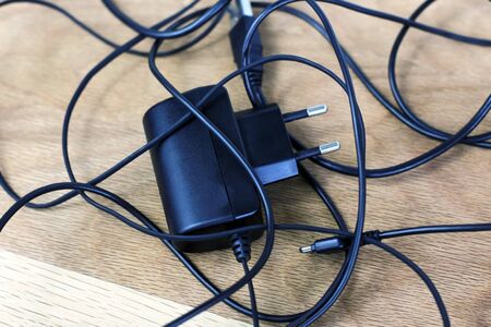 tangled charger wires. Black wire on a wooden backgroundの写真素材