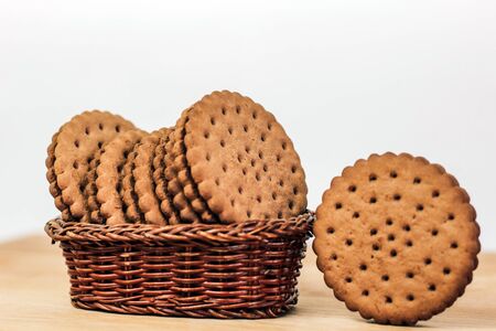 crispy chocolate cookies with holes in a basket on a wooden boardの写真素材