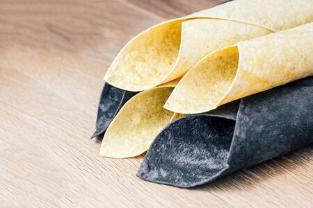 thin pita bread white and black rolled up by a straw. Chorny pita with cuttlefish ink and Armenian traditional pitaの写真素材