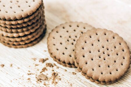 Crispy chocolate chip cookie with holes on a wooden board. Filled Round Cookiesの写真素材