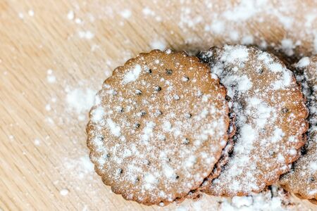 Crispy chocolate chip cookie with holes on a wooden board. Round cookies stuffed with powdered sugarの写真素材