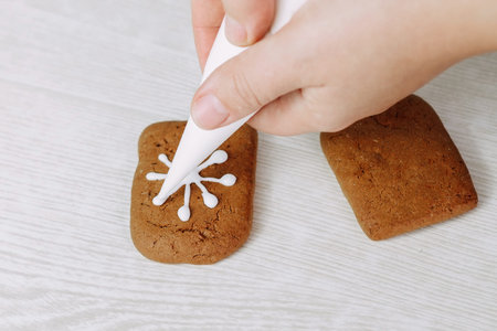 Christmas gingerbread cookies painted with icing sugar. Confectioner girl paints cookies