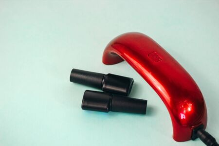 UV lamp and gel nail polish. manicure flat on a turquoise backgroundの写真素材
