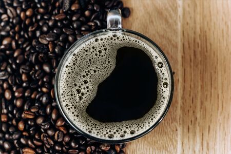 a lot of coffee beans on a wooden background. Cup of freshly brewed black coffeeの写真素材