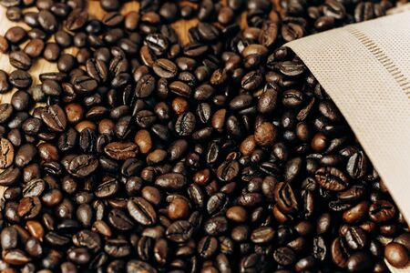 many coffee beans on a wooden background in an ecology bagの写真素材