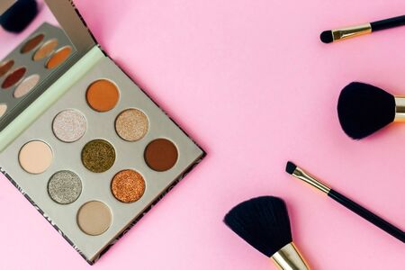 Multi-colored pastel brown red eye shadow on a pink background with brushes.の写真素材