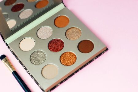 Multi-colored pastel brown red eye shadow on a pink background with brushes.の写真素材