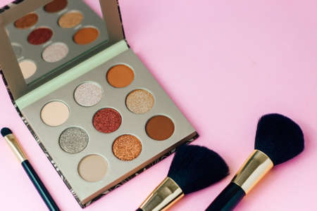 Multi-colored pastel brown red eye shadow on a pink background with brushes.の写真素材