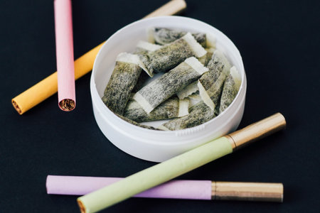 Round box of snus with multicolored cigarettes Cigarette substitute, nicotine pouches.