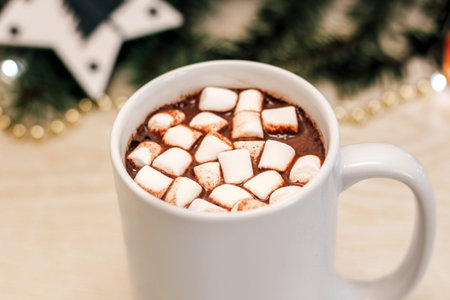Marshmallows in cocoa in a cup on the background of a Christmas tree.