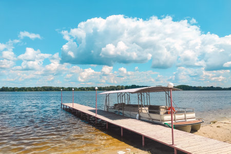 Pleasure river boat moored to the shore. Summer sunny river landscape with catamaran.の写真素材