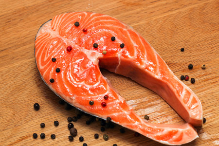 Fresh salmon steak on a wooden board with spices and pepper. Preparing for cooking.の写真素材