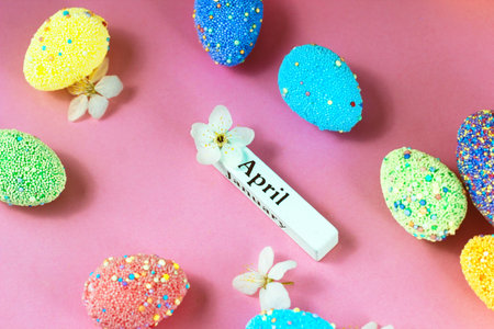 April lettering with Easter eggs and spring flowers on a pink backgroundの写真素材