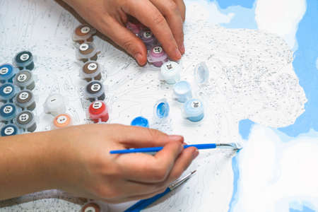 Girl paints with acrylic brush by Number Kits.の写真素材