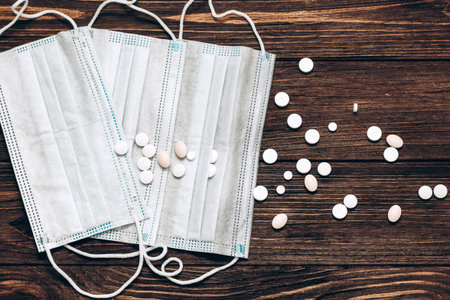 medical mask and pills on wooden background.