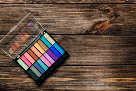 Multi-colored palette of eye shadows on a wooden background. Make-up for the eyelids.の写真素材