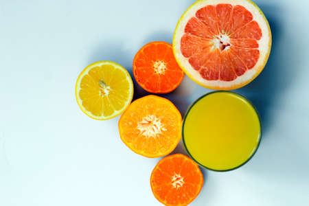 Sliced citrus on a white background with a glass of fresh juice. Grapefruit, lemon, tangerineの写真素材
