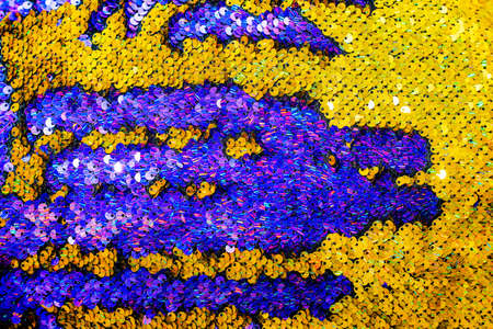 The shiny bright texture of the sequins changes color. Purple and yellow. Fabric for fancy dresses.の写真素材