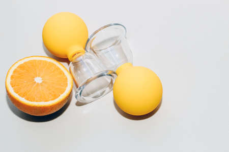 Vacuum massage anti-cellulite cups on a gray background with an orange. Self-massage for healthy skin.の写真素材