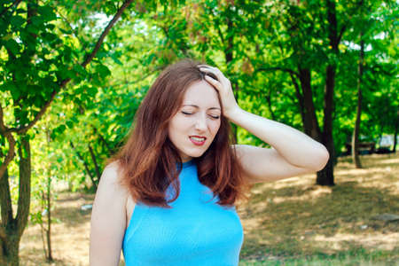 Young pretty girl with red hair holding her head, it became bad on the street.の写真素材