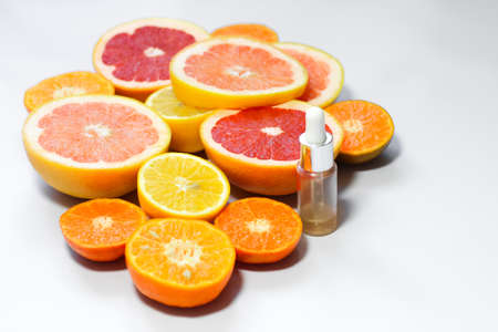 Face serum with vitamin c with different citrus fruits on a white background.の写真素材