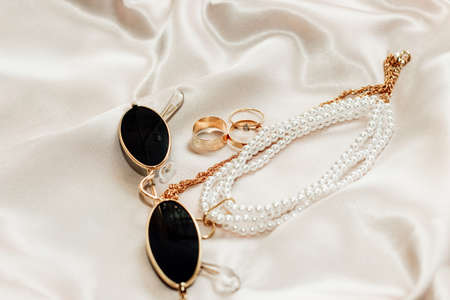 Flatley with gold jewelry and pearls on a silk background, glasses in the frameの写真素材