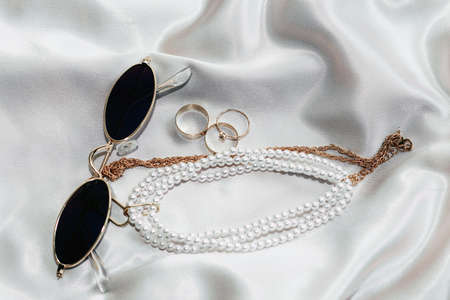 Flatley with gold jewelry and pearls on a silk background, glasses in the frameの写真素材